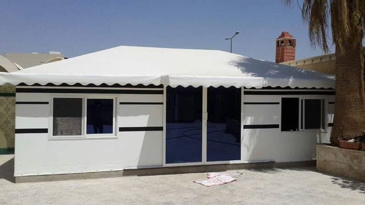 بيوت شعر الجبيلة بواجهة بيضاء مخططة ومدخل مركزي ونوافذ في فناء سكني